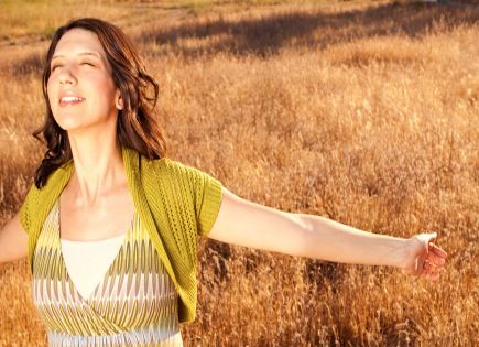 Woman basking in light in wheat field.