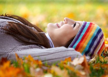 Young woman laying on dry leaves and setting her imagination free