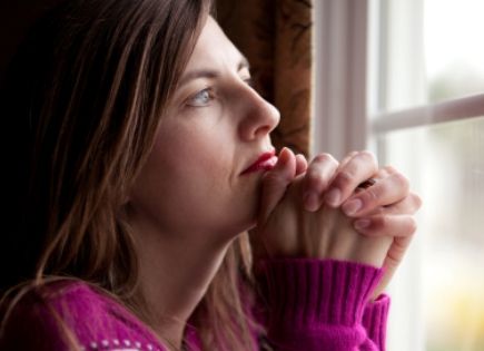 woman praying looking ou window