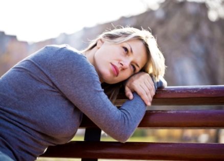 woman resting her head on a bench in warm sunlight