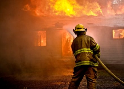 Firefighter attempting to extinguish a blazing fire.