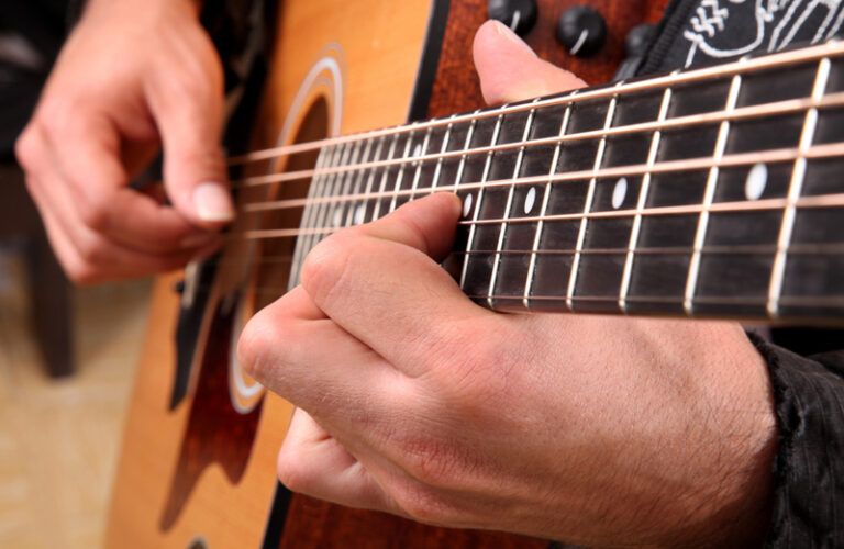 A close-up shot of a man's hands playing a guitar