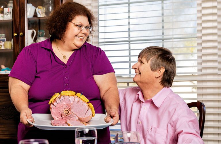 Lori Durham places an Easter ham on the table for her husband, John.