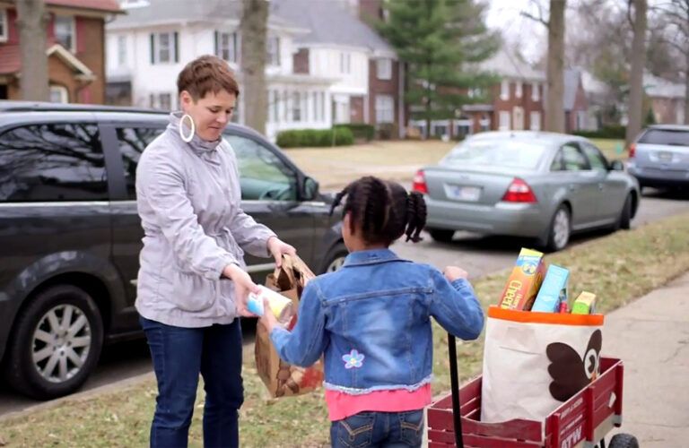 A little girl collecting food to be donated receives a contribution.