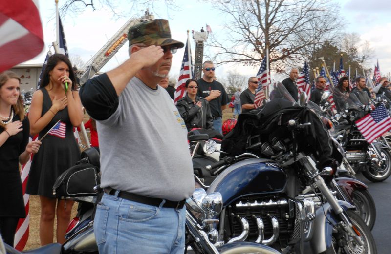 A line of Patriot Guards saluting at a fallen Army medic's funeral