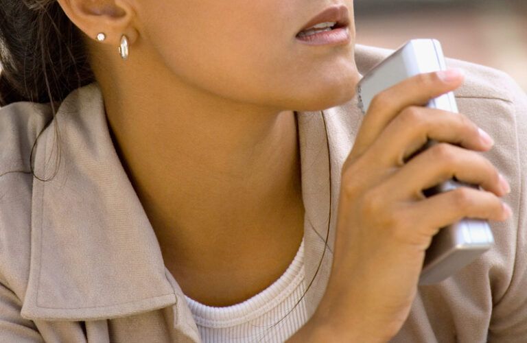 A young woman records a message in a handheld tape recorder.