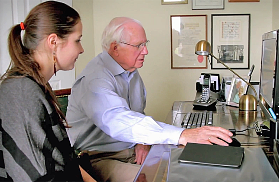 A teenager helps an elderly man to use facebook.