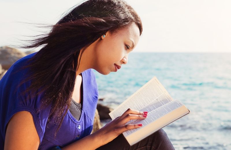 woman reading the Bible by the ocean