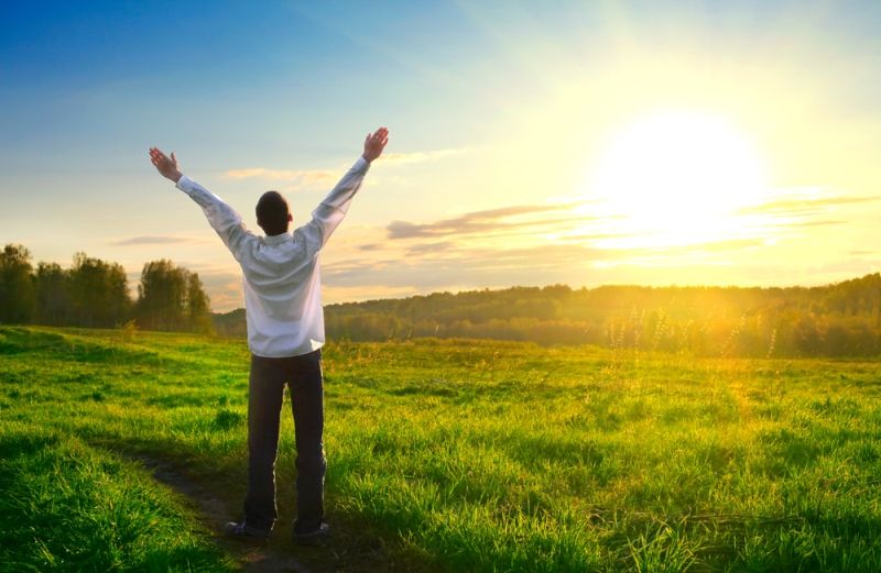 Man with arms outstretch at sundown.