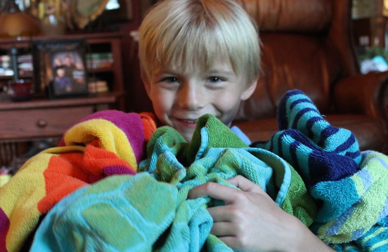 Shawnelle's son Zay holds a jumble of towels.