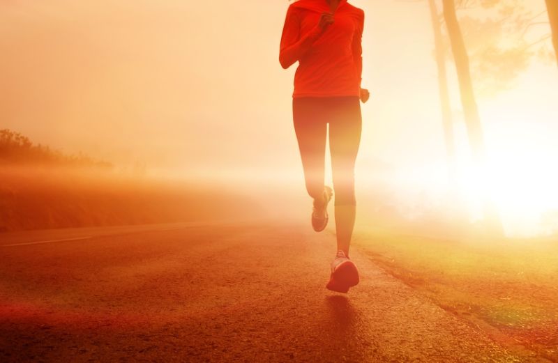 A woman running as the sun rises.