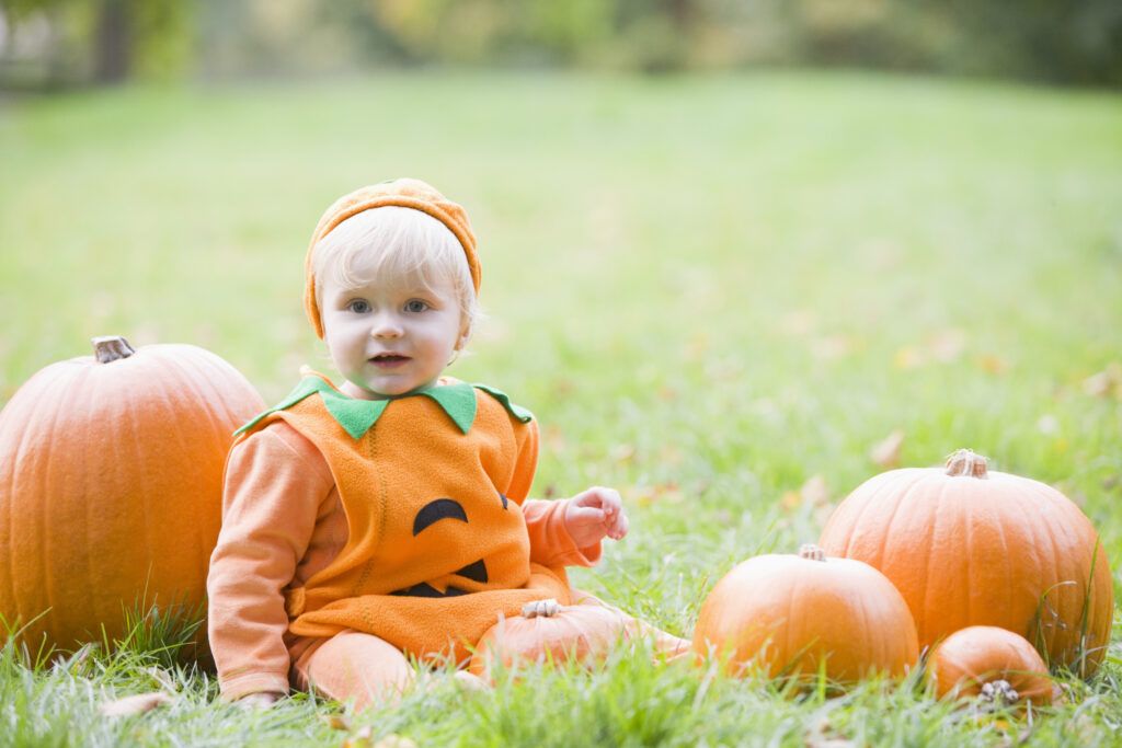 Child in a Halloween pumpkin costume in a field of pumpkins