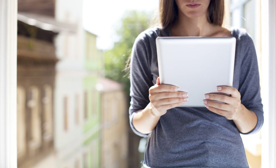 A woman reads email on her tablet.