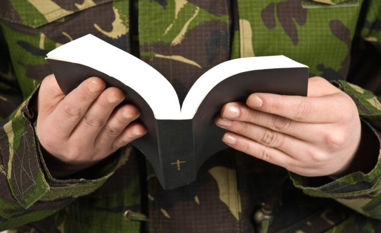 A soldier in camouflage fatigues reads the Holy Bible.