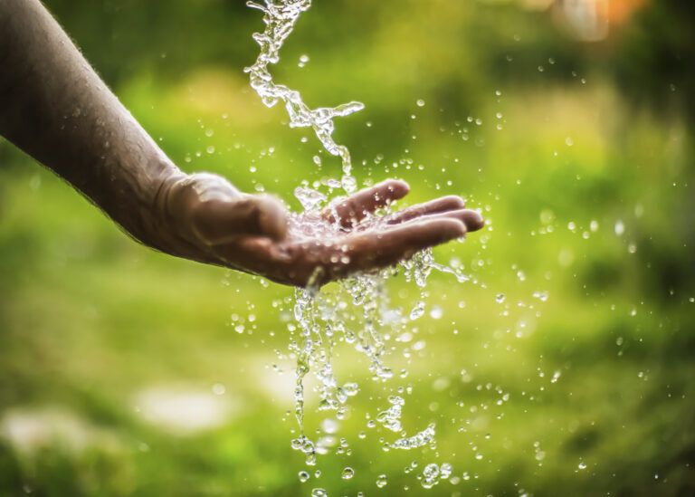 A man reaches his hand into a downward stream of water