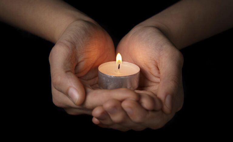 Woman's hands cupping a candle. Photo by Goo Dween123, Thinkstock.