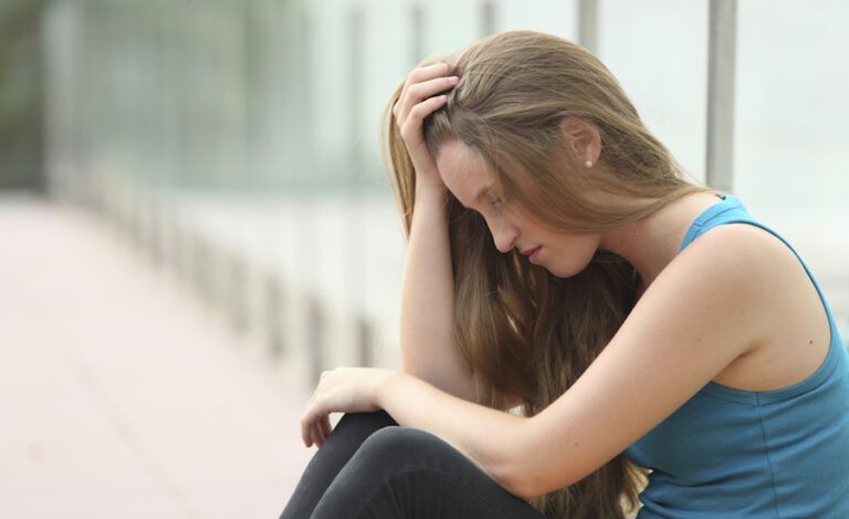 Girl sitting in school hallway. Photo: Thinkstock.