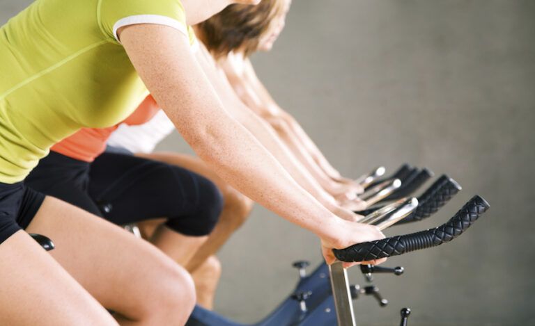 Two sisters support each other at a SoulCycle spinning class.