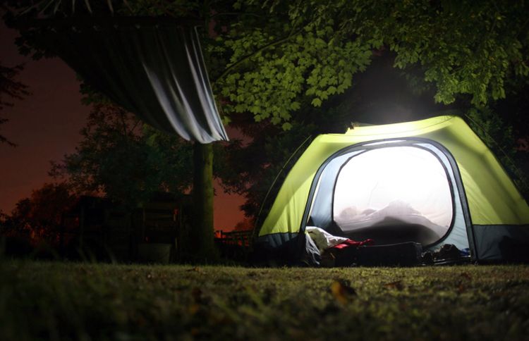 A family enjoys time together in a glowing tent in the back yard