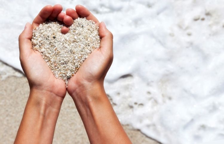 Hands holding sand in a heart-shape to symbolize Jesus' love for us