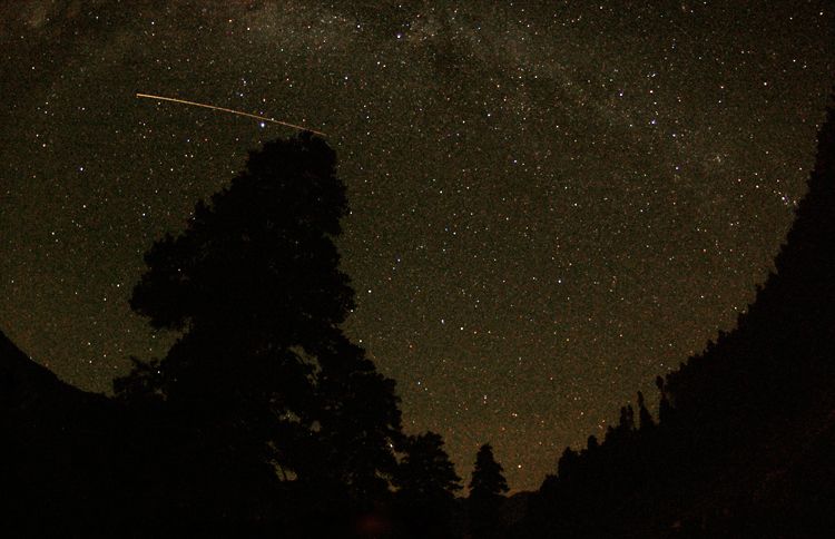 A falling star streaks across a summer sky.