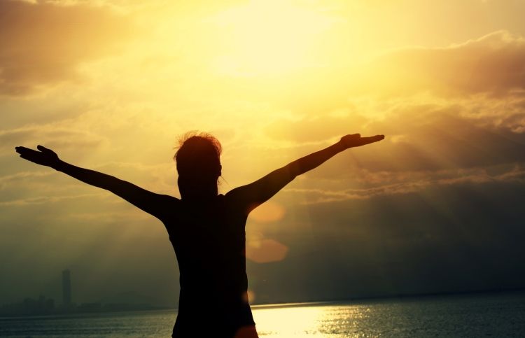 Woman prays to God as the sun rises.