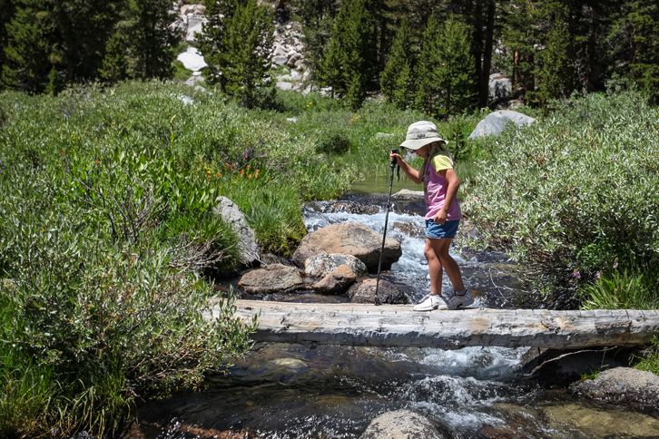 Guideposts: Rebekah walks across a log to cross a creek.