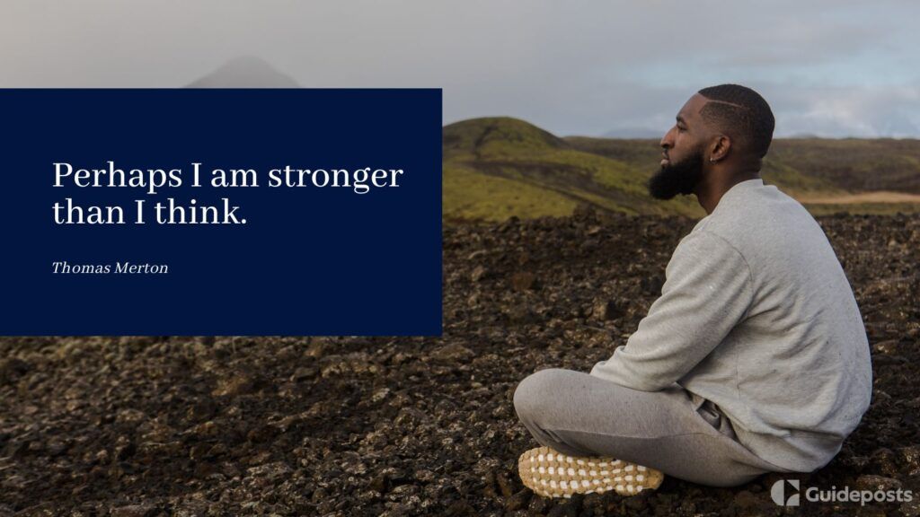 A man sitting on a rocky landscape with a veterans day quote by Thomas Merton