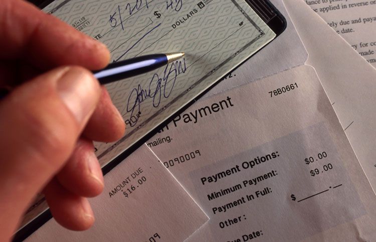 A female signs a check to pay a bill