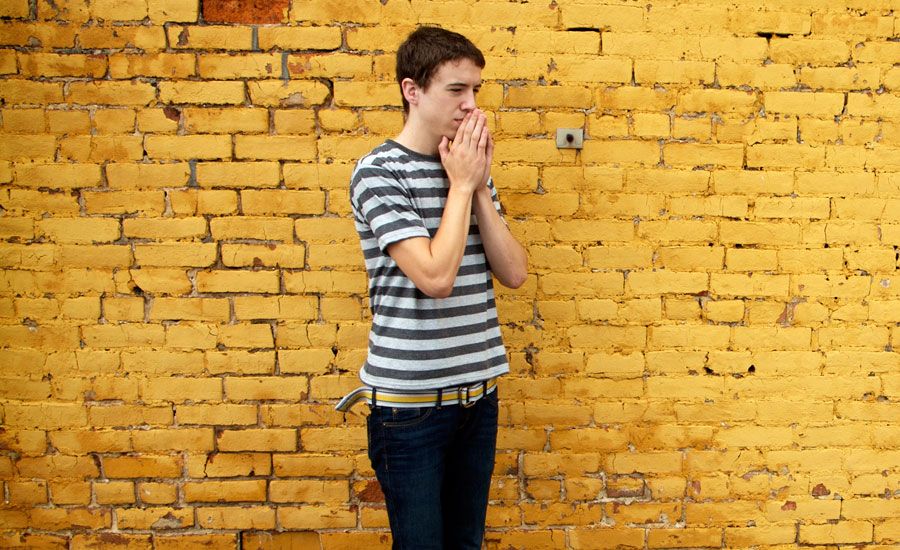 A young man bows his head in prayer