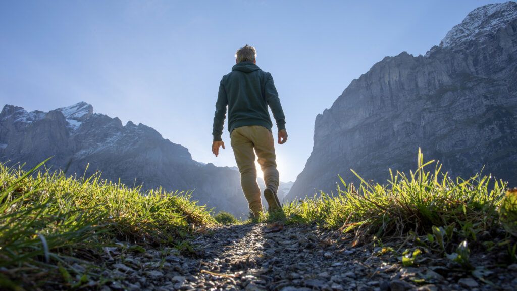 Man walking on a trail at sunrise with New Year quote about God