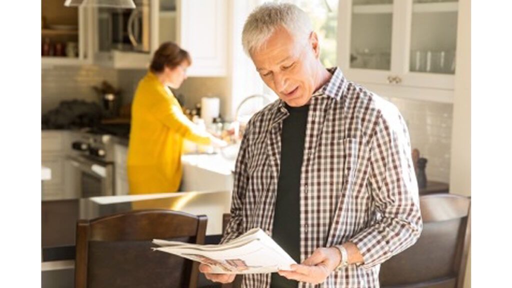 Elderly man reads a newspaper article