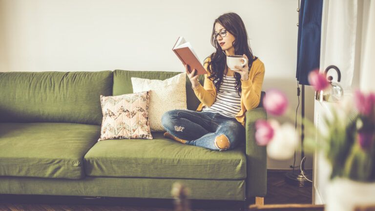 Young woman reading the book of Bible verses about spring with tulips in her home