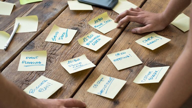 A woman's cluttered desk is plastered with post-it notes.