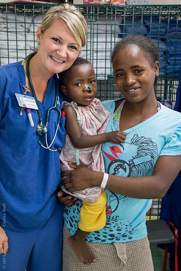 Heather poses with a young patient and his mother