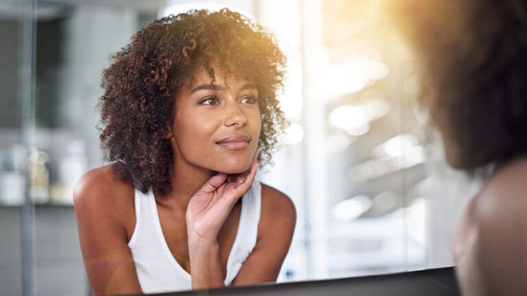 Woman looking at her reflection in a bathroom mirror