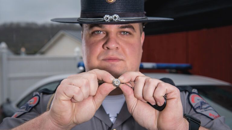 Adam displays the engraved metal button that saved his life