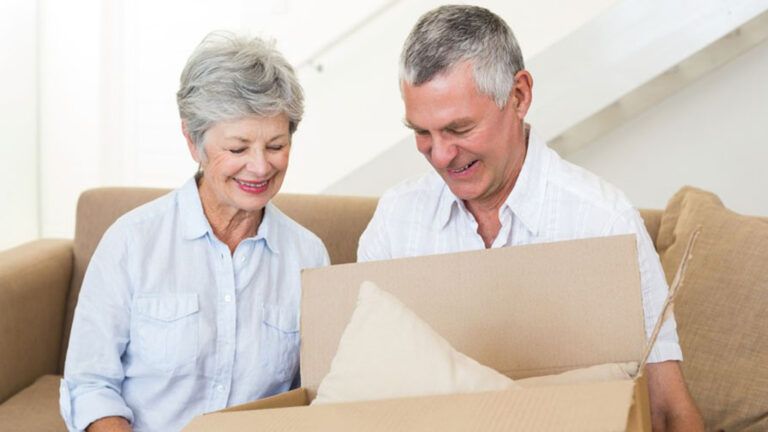 A older couple packs their belongings in moving boxes.