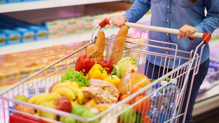 A woman with a shopping cart full of groceries.