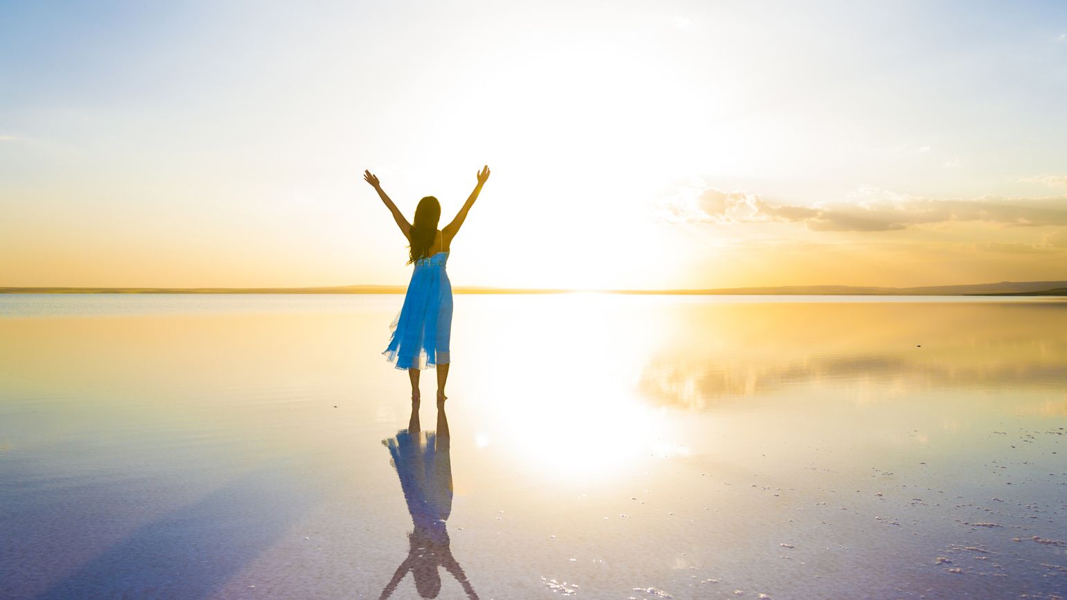 Silhouette of a woman with her arms raised to the sun