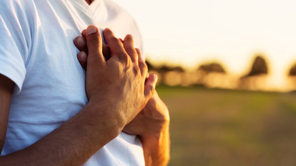 A man clasps his hands to his heart