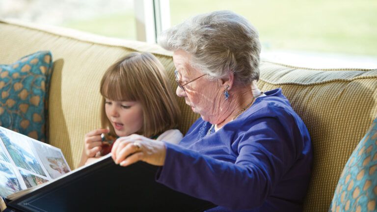 A senior citizen woman reads to one of the preschoolers.