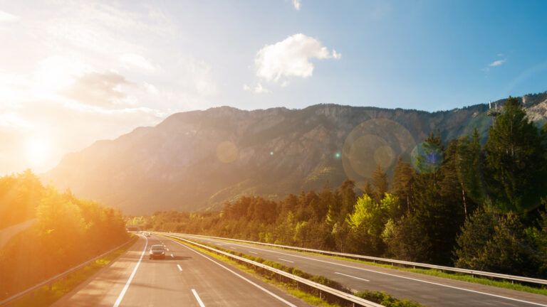 A few cars on a scenic highway illuminated by soft sunlight