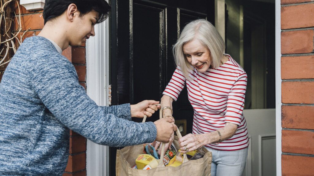 young boy helps older woman with bags, Getty Images