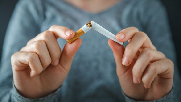 A woman breaks her cigarette in half