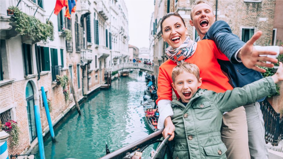 A family taking a selfie on vacation in Venice while saying prayers for safe travel