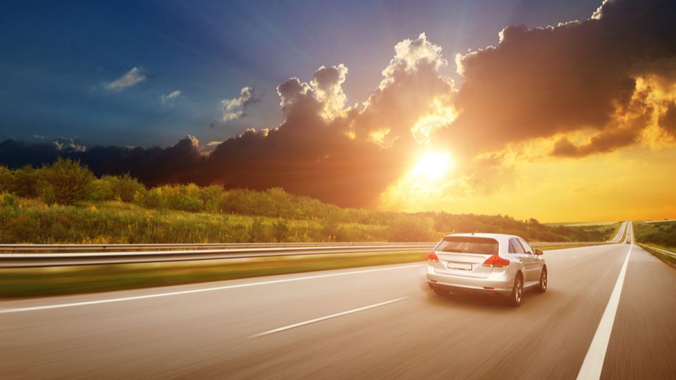 A car driving on the road at sunset with prayers for safe travel