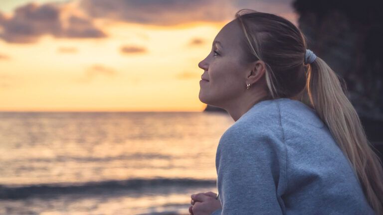 A woman gazes contentedly out at the ocean