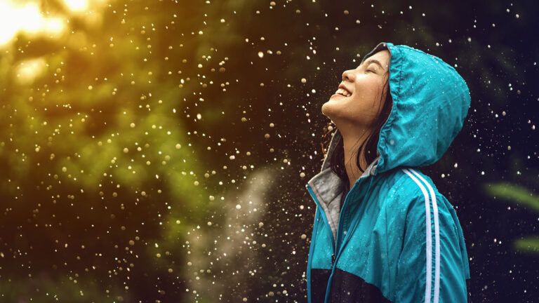 A woman smiles joyfully, enjoying a summer shower