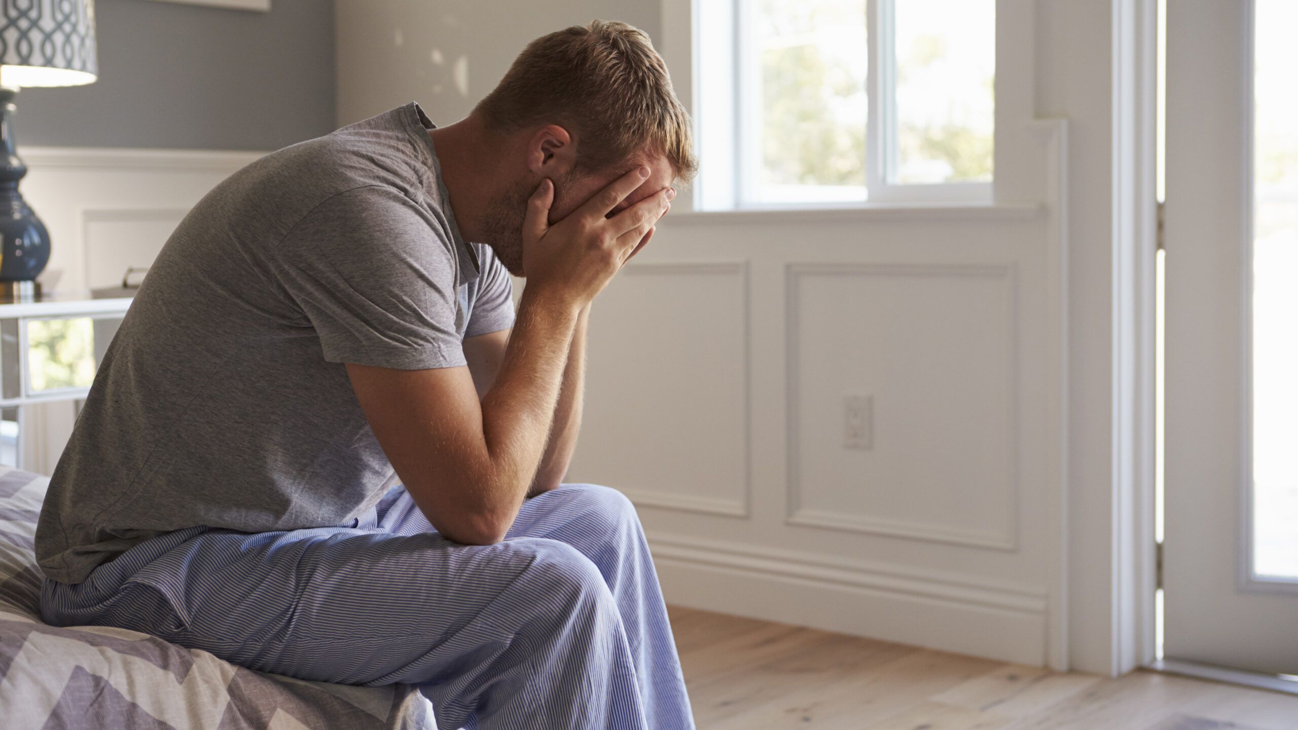 Man in pajamas with face in hands